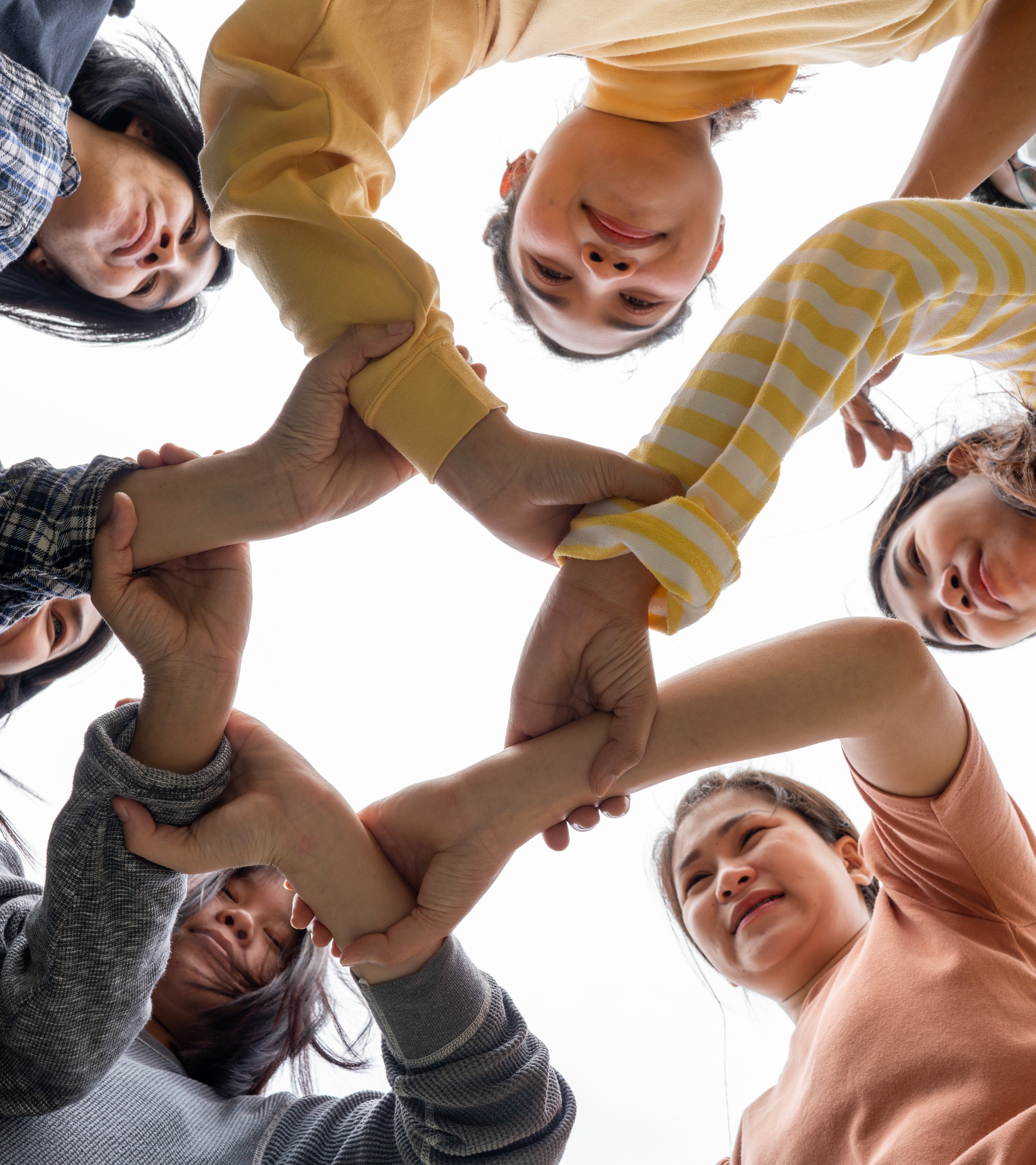 Diverse group of young people joining hands in a circle, symbolizing unity and community collaboration